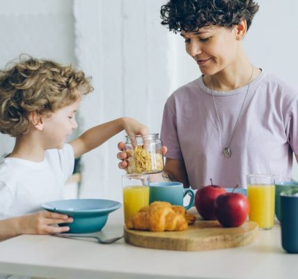 Happy family mother and son eating cereal with milk at home talking