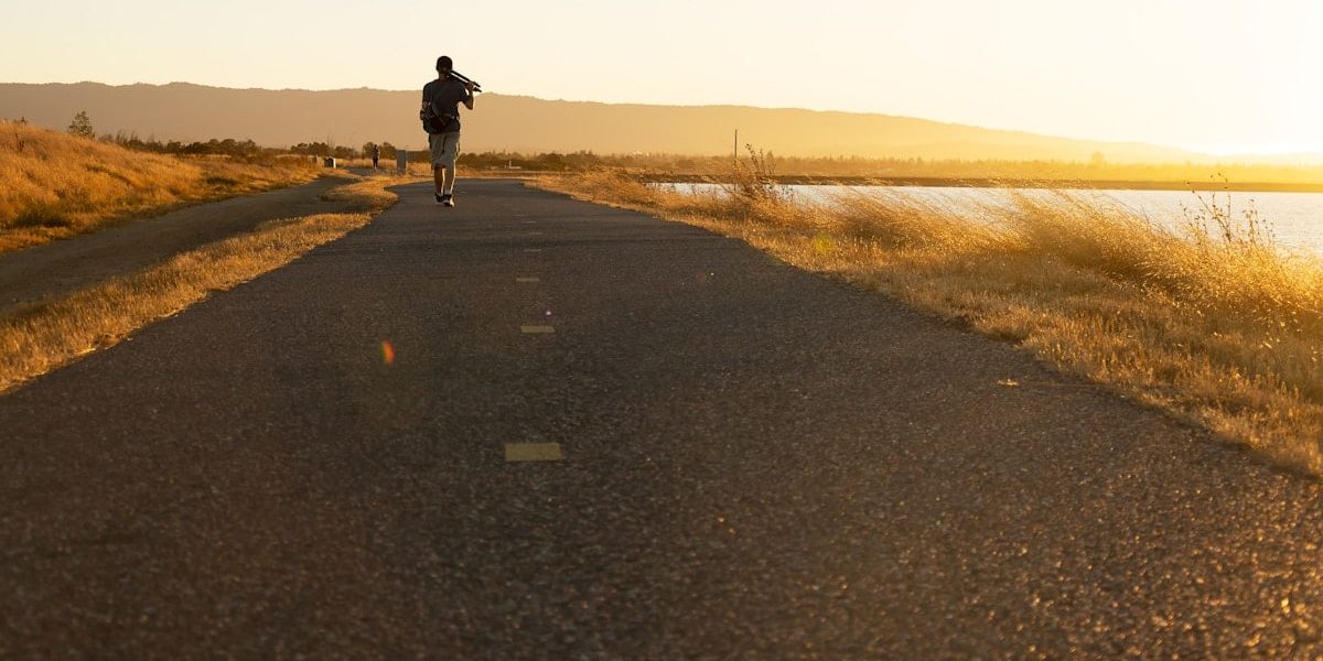 Man walking on trail agains the sunset.