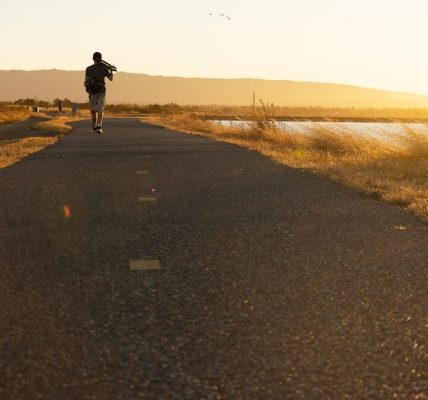 Man walking on trail agains the sunset.