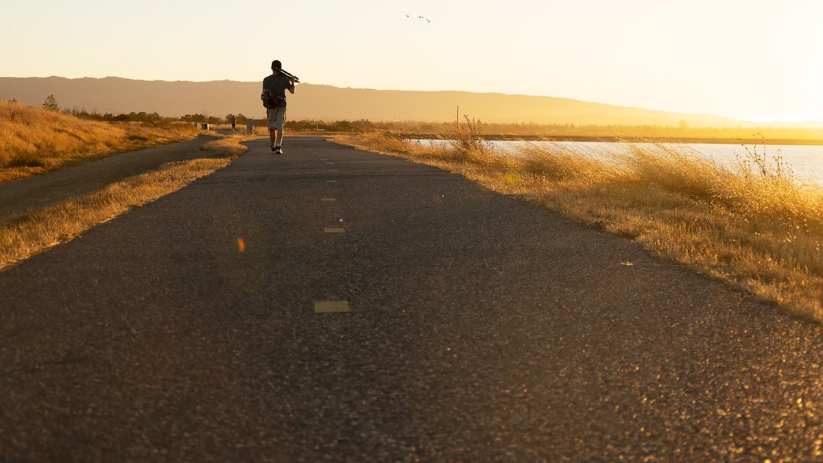 Man walking on trail agains the sunset.
